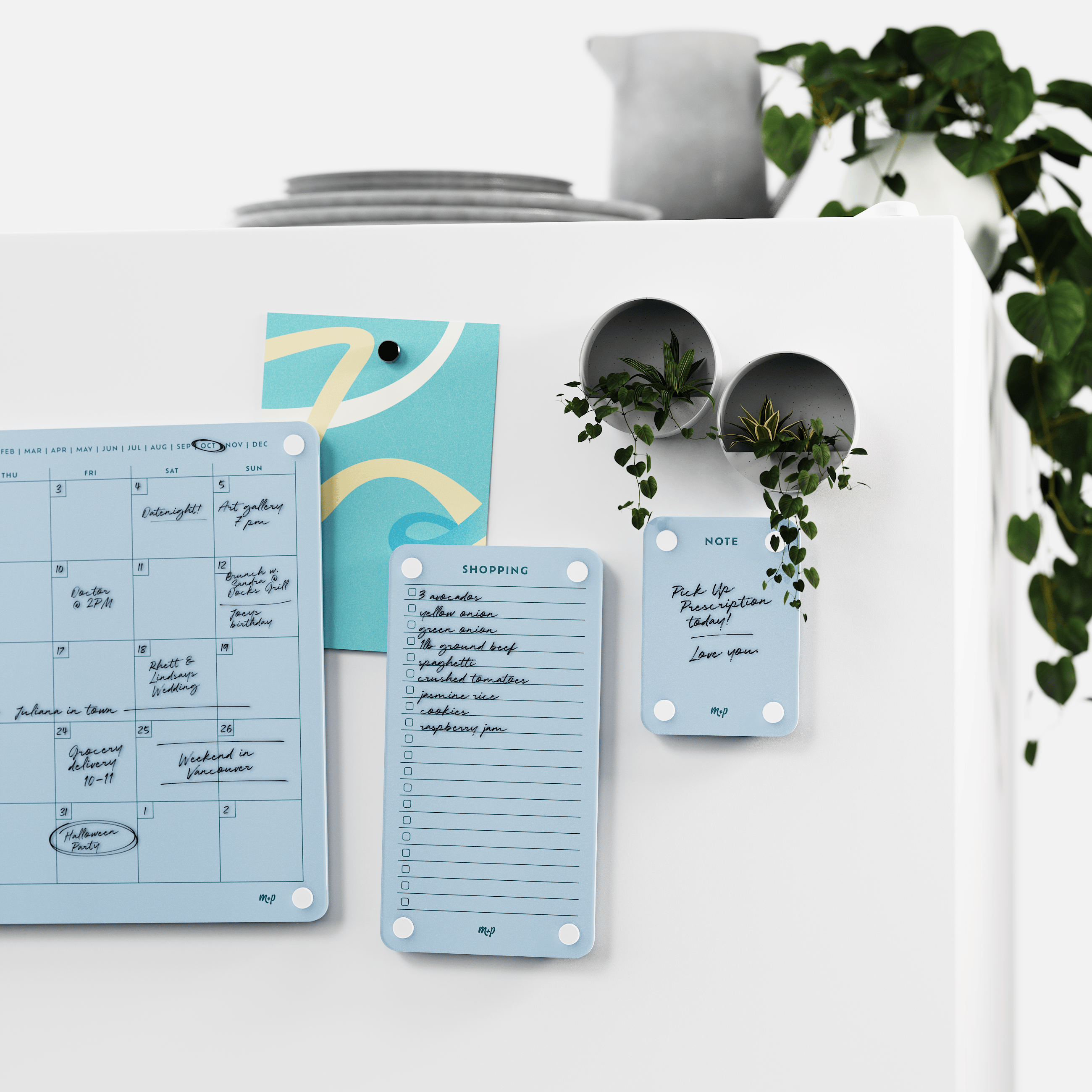 Vista blue calendar, shopping list and note board on a white wall beside two magnetic planters